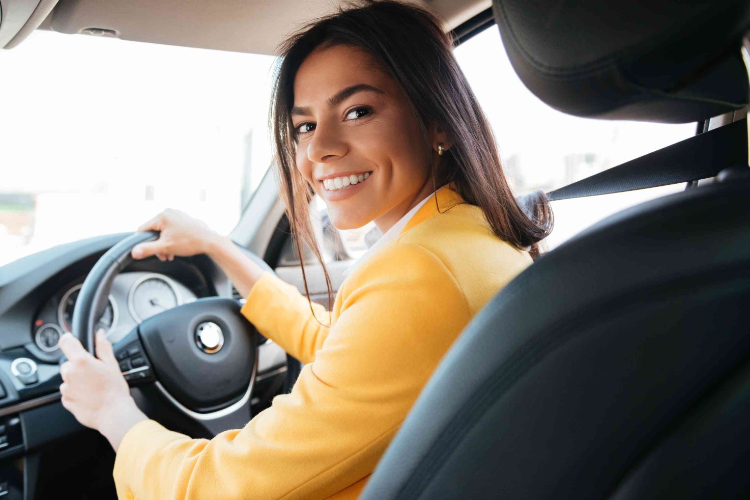 Woman in a car smiling because she's found the perfect storage solution for her car